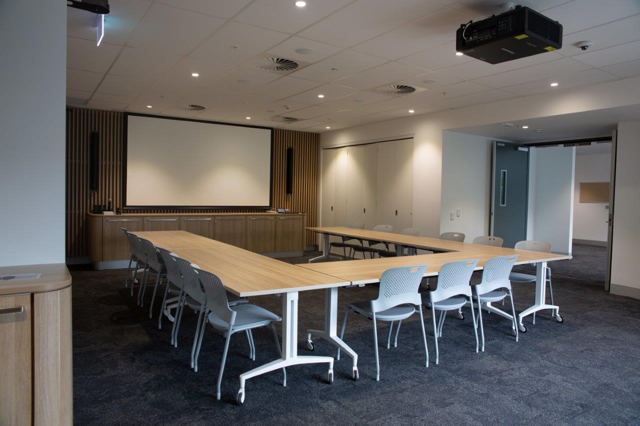 Events Space with Large Tables and Chairs, Projector and Screen.