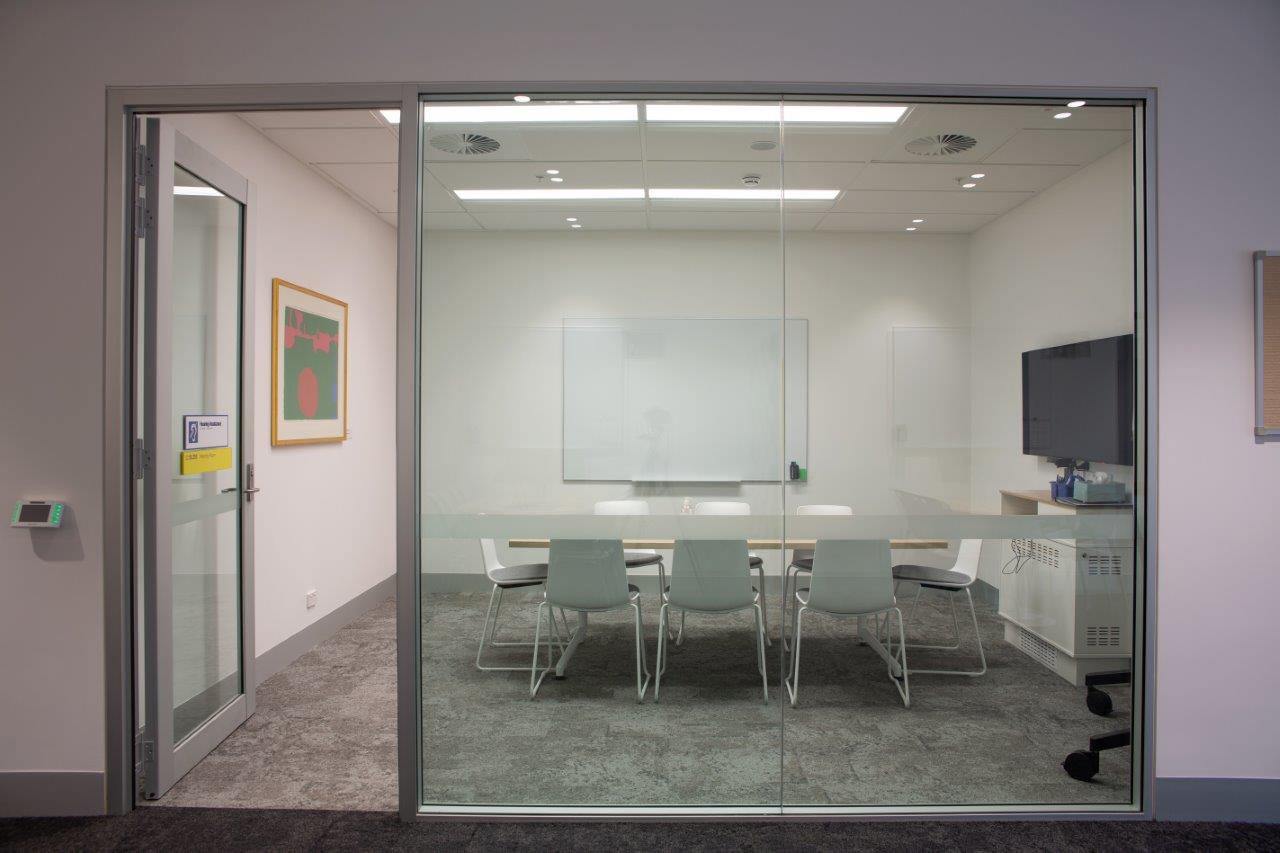 Meeting room with table, chairs, whiteboard and screen.