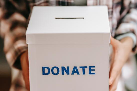 person holding donation box with the word donate in blue