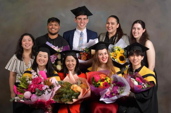 Happy graduating students in gowns with flowers 