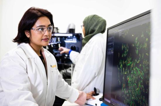 Researcher in lab coat looking at screen