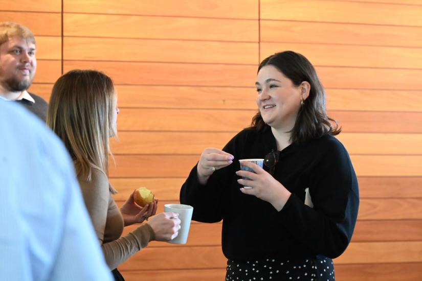 Two women standing having a conversation while holding cups.