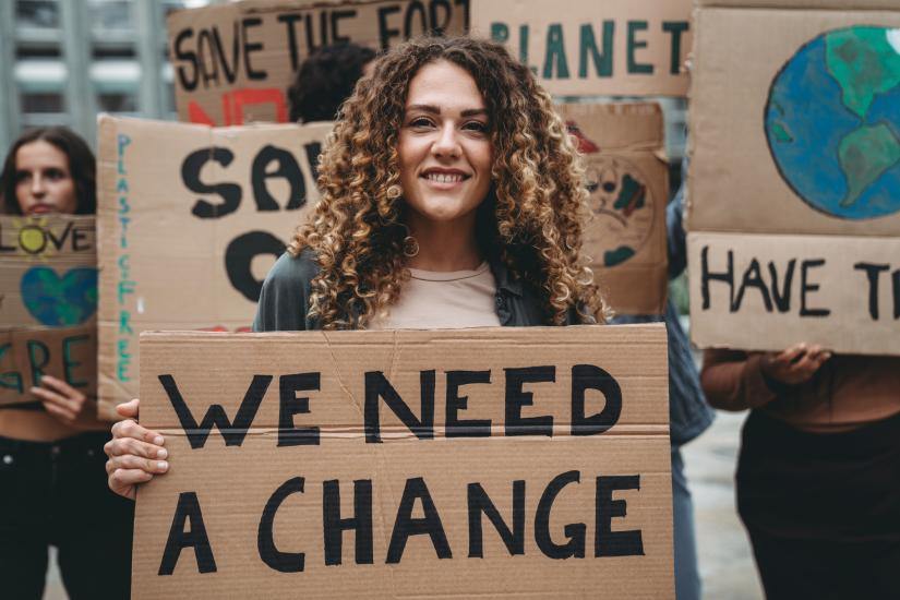 woman holding poster that says "we need change"