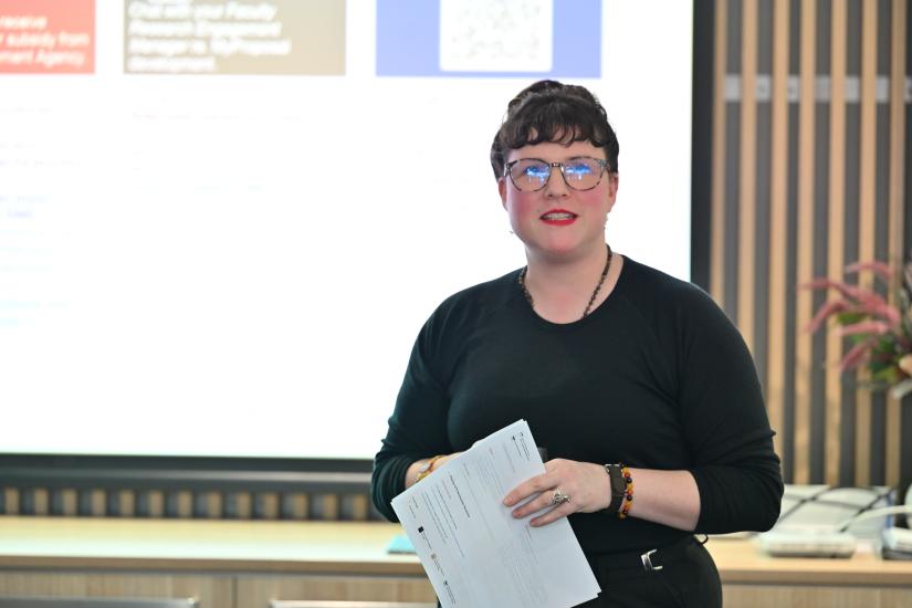 woman holding document in front of screen
